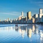 Stunning view of Balneário Camboriú's modern skyline reflecting on the beach at daytime.